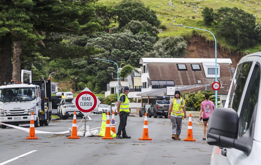 Photo by DJ MILLS / AFP  Emergency workers close a road following a landslide while a search is underway by local emergency services for missing people at Mount Maunganui in Tauranga on January 22, 2026.