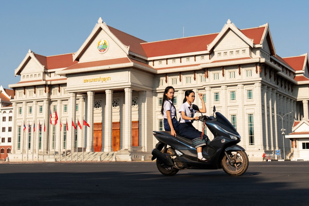 Photo by STR / AFP  Motorists drive past the Lao National Assembly ahead of the election in Vientiane on February 19, 2026.