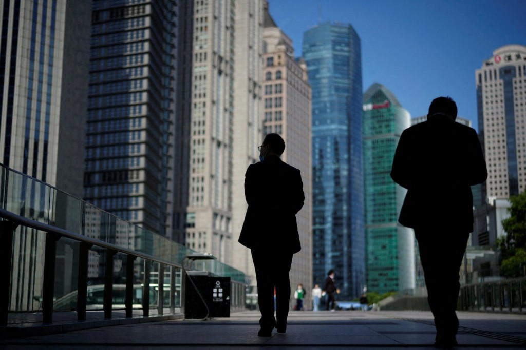 People walk by office towers in the Lujiazui financial district of Shanghai, China October 17, 2022. REUTERS