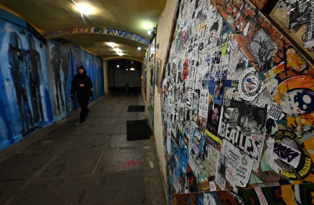 A woman walks past graffiti at the Pushkinskaya 10 Art Center in Saint Petersburg on October 27, 2025. (Photo by Olga MALTSEVA / AFP)