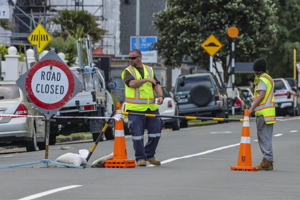 Emergency workers close a road following a landslide while a search is underway by local emergency services for missing people at Mount Maunganui in Tauranga on January 22, 2026.