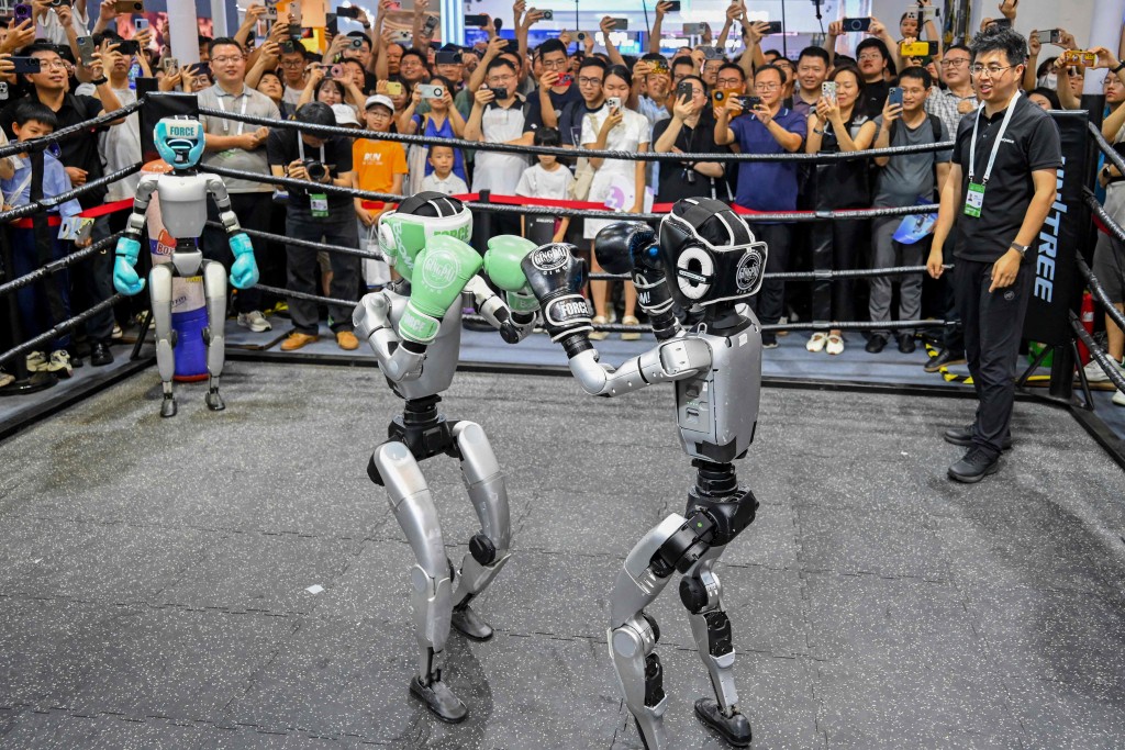 People watch humanoid robots boxing at an exhibition during the World Artificial Intelligence Conference in Shanghai on July 26, 2025. (AFP Photo)