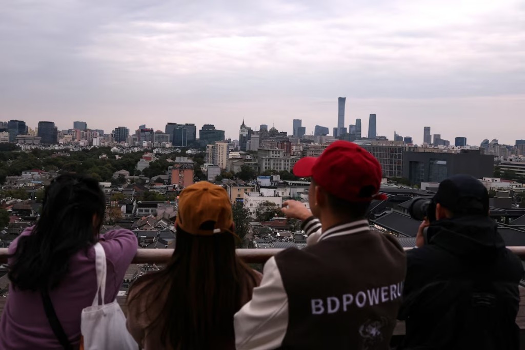 People look at the city skyline at a rooftop of a building in Beijing, China October 18, 2025. REUTERS