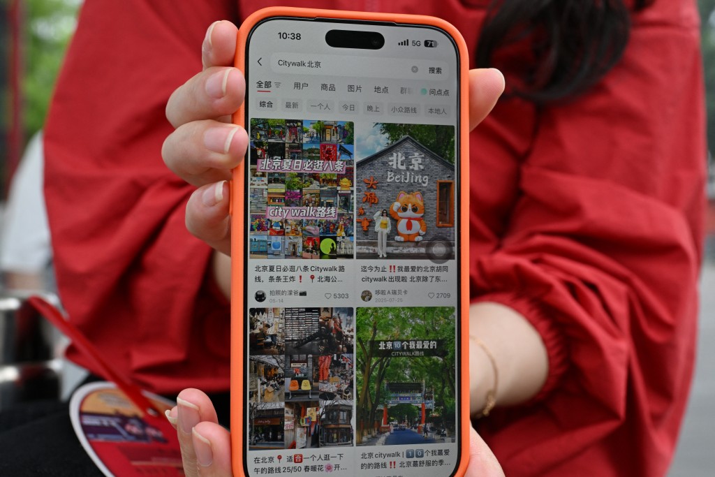 A tourist from Hunan province shows her Xiaohongshu account on her mobile phone while visiting the Forbidden City in Beijing on July 11, 2026. Competition is fierce for professional photographers at Beijing's tourist hotspots, including a scenic lake where women in flowy traditional robes pose for snaps to share on Xiaohongshu, China's massively popular lifestyle app. The platform, known as RedNote in English, has shaken up the tourism industry in China, where domestic travel is booming to record levels.