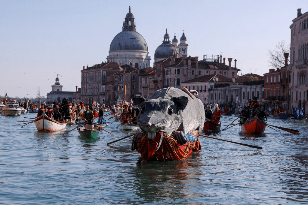 A boat carries a "Pantegana", the big rat, as revellers row during the masquerade parade on the Grand Canal during the Venice Carnival, in Venice, Italy, February 1, 2026. REUTERS/Claudia Greco/File Photo