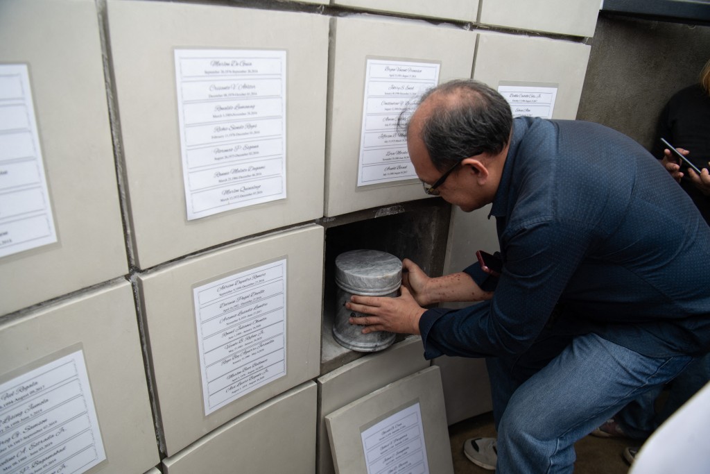 Photo by TED ALJIBE / AFP  Randy delos Santos, a volunteer at the "Dambana ng Paghilom Center" (Shrine of Healing) places one of the urns, a victim of extrajudicial killings of former Philippine president Rodrigo Duterte's drug war, during the inurnment rites at a cemetery in Caloocan city, suburban Manila on February 20, 2026.