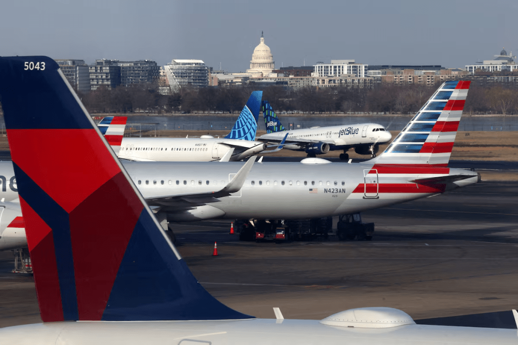 A JetBlue aircraft lands under the DC skyline featuring the U.S. Capitol building, near United Airlines, American Airlines and Delta Airlines aircraft on the tarmac at Ronald Reagan Washington National Airport in Arlington, Virginia, U.S. January 25, 2025. REUTERS/Jim Urquhart/File Photo