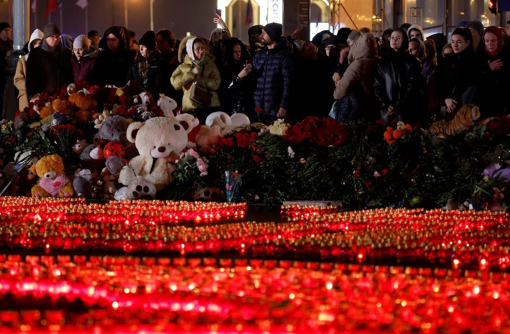 People stand in front of lit candles outside the Crocus City Hall concert venue on the day of mourning declared following a deadly shooting, in the Moscow Region, Russia, March 24, 2024. (REUTERS/Maxim Shemetov)