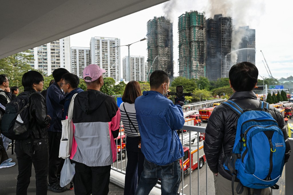 Photo by PETER PARKS / AFP  People watch the still burning Wang Fuk Court residential estate in Hong Kong's Tai Po district on November 27, 2025.