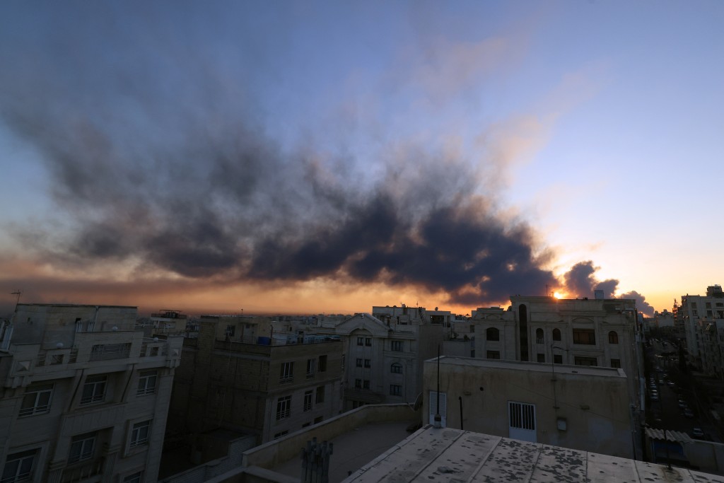The sun is seen setting through a plume of smoke following a strike on the Iranian capital Tehran, on March 3, 2026. (AFP)
