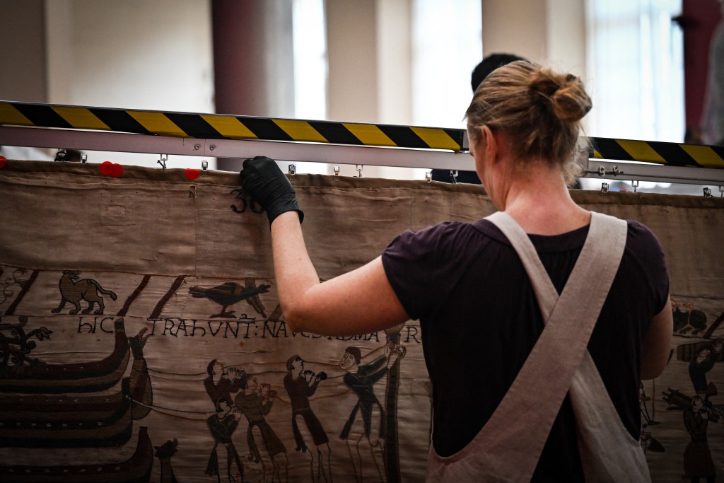 Photo by LOU BENOIST / POOL / AFP  A worker prepares to pack the Bayeux Tapestry in a crate for transfer to the British Museum, at the Bayeux Tapestry Museum, in Bayeux, northwestern France, on September 18, 2025.