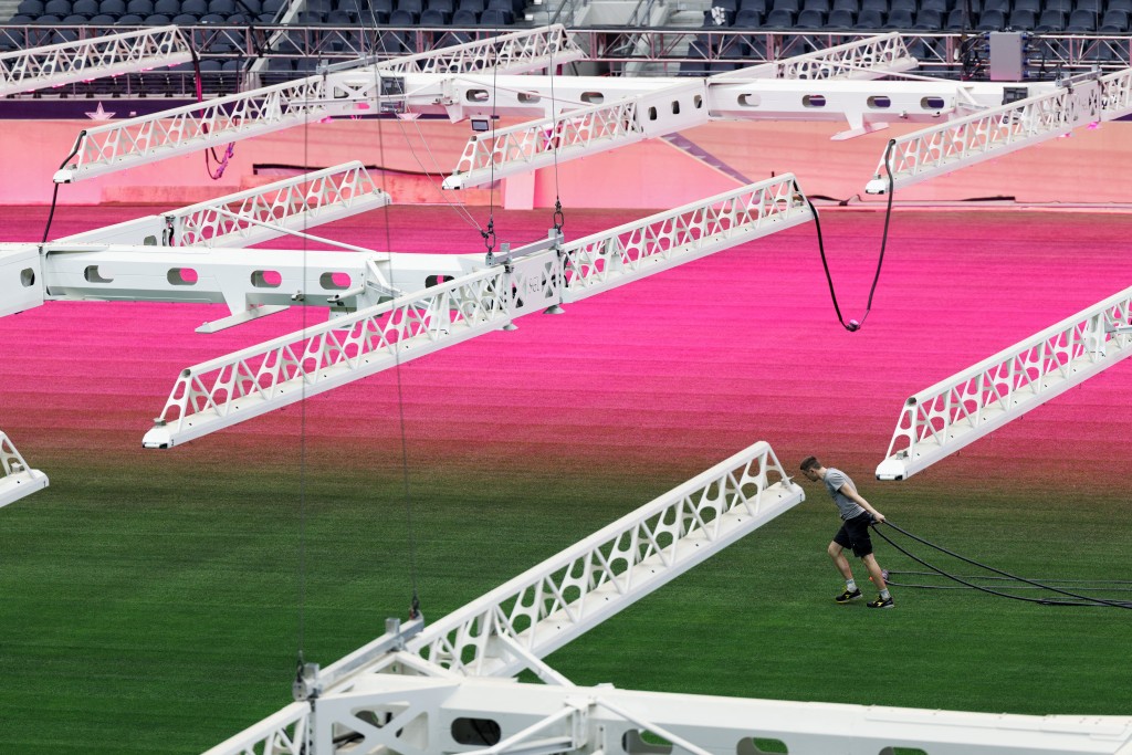 Photo by MARK FELIX / AFP  Pink lights illuminate newly laid grass on the pitch inside AT&T Stadium, which will be called "Dallas Stadium" during the duration of the tournament, in Arlington, Texas on May 18, 2026.
