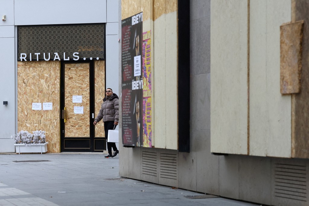 A man walks past stores protected with wooden panels in Lyon, ahead of nationwide protests against the cost of living and rising fuel prices in France, October 23, 2026. REUTERS/Lisi Niesner 