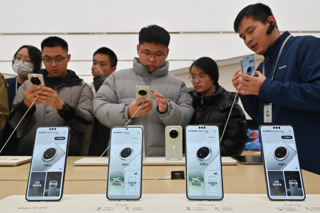People check Huawei's new Mate 70 mobile phone inside a shop at the Wangfujing shopping area in Beijing on November 26, 2024. Chinese tech giant Huawei on November 26 unveiled its first smartphone equipped with a fully homegrown operating system, a key test in the firm's fight to challenge the dominance of Western juggernauts. (Photo by ADEK BERRY / AFP)