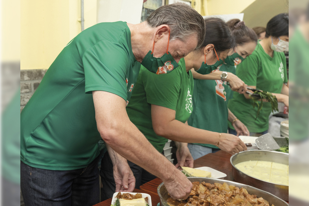 Ian McLeod, Chief Executive of DFI Retail Group (left), set an example by taking part in preparing meal boxes for the needy.
