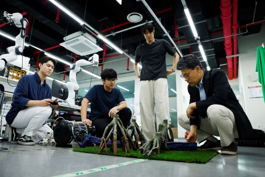 Park Shinwoo, PhD student of Civil and Environmental Engineering at the Korea Advanced Institute of Science and Technology (KAIST), Kim Nam Gyun, a postdoctoral researcher at KAIST and a soft robotics engineer, Hwang Jae Yun, a graduate student of Civil and Environmental Engineering at KAIST, and Ryu Jee-Hwan, a professor of civil and environmental engineering at KAIST, demonstrate a soft-growing robot as it extends between model tree branches at KAIST in Daejeon, South Korea, July 14, 2026. REUTERS/Kim Soo