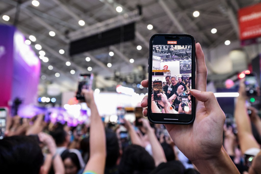  Visitors record Nvidia CEO Jensen Huang on their mobile phones during Computex 2026 in Taipei on June 3, 2026. (Photo by I-Hwa Cheng / AFP)