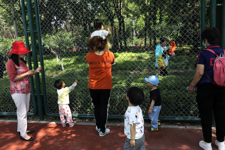 Children play next to adults at a park in Beijing. (Reuters) Children play next to adults at a park in Beijing. (Reuters)