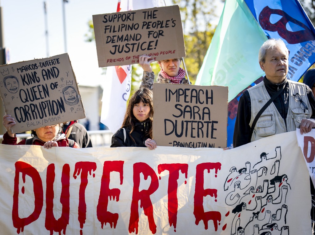 Photo by SEM VAN DER WAL / ANP / AFP  Protesters hold placards in front of the International Criminal Court (ICC) ahead of the ruling on the appeal by the former Philippines President Rodrigo Duterte.