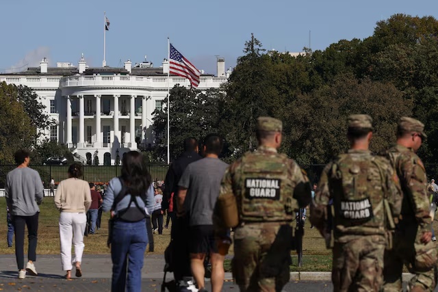 National Guard members and visitors walk near the White House, weeks into the ongoing U.S. government shutdown, in Washington, D.C., U.S., October 22, 2025. REUTERS/Kylie Cooper 