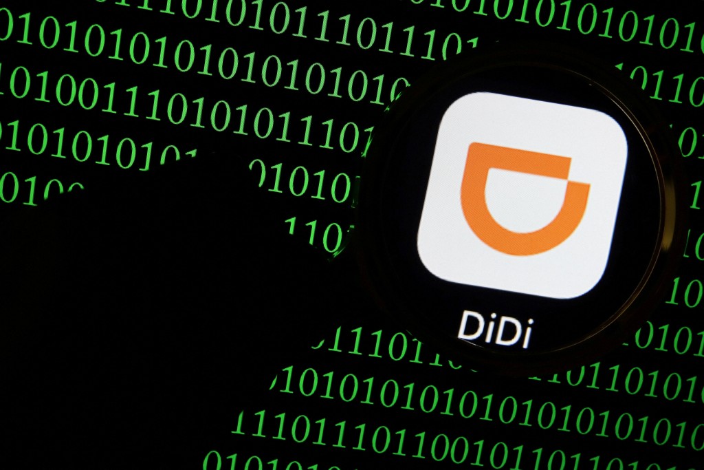 The app logo of Chinese ride-hailing giant Didi is seen through a magnifying glass on a computer screen showing binary digits in this illustration picture taken July 7, 2021. REUTERS