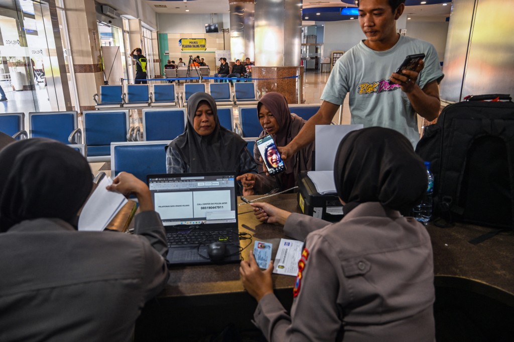 Police officers ask information from Ela Nur Atika (L), a wife of a passenger of the Virgo Transport 8, carrying 243 people, which met with an accident en route from Surabaya, East Java to Banjarmasin, South Kalimantan. (AFP)