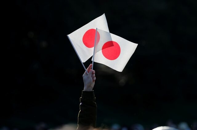 A well-wisher holds Japan's national flags during Emperor Naruhito's public appearance for New Year celebrations at the Imperial Palace in Tokyo, Japan, January 2, 2020. REUTERS/Kim Kyung-Hoon