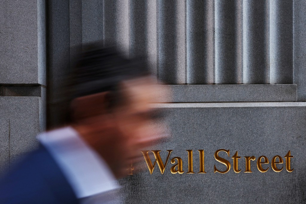 A man walks past a Wall Street marking outside the New York Stock Exchange (NYSE) building on Tuesday following Monday’s broad sell off in New York City, U.S. (Reuters)