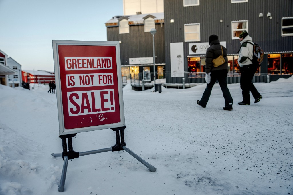 People walk past a sign placed on a street in Nuuk, Greenland, Tuesday, January 20, 2026. (Reuters)