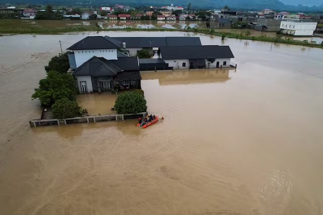 A drone view shows rescuers using an inflatable boat to evacuate locals at a residential area affected by floods following heavy rains in Meureudu, Pidie Jaya regency, Aceh province, Indonesia, November 27, 2025. REUTERS/Hidayatullah Tajuddin 