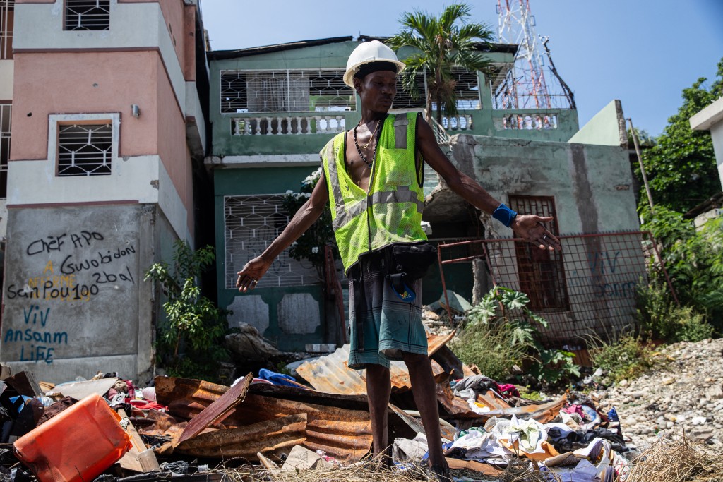 A worker gestures as he cleans a street on September 25, 2025 in the Delmas 30 neighborhood, which was attacked by gangs in late 2024 and early 2025, in Port-au-Prince, Haiti. Violence-ravaged Haiti is a nation "at war," its leader Laurent Saint-Cyr warned at the United Nations on Thursday, as he appealed for help from the international community to defeat gangs that have overrun the Caribbean country. (Photo by Clarens SIFFROY / AFP)