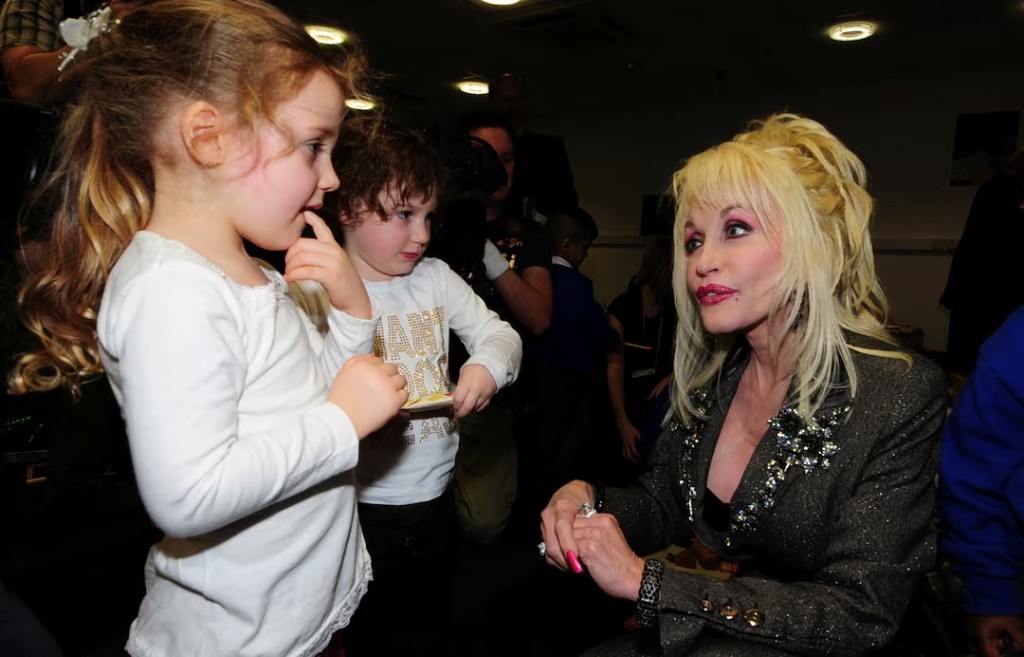 U.S. singer Dolly Parton (R) speaks to children at the launch of her Imagination Library book project at the Magna Centre in Sheffield in northern England December 5, 2007. Parton's Imagination Library project is an early literacy programme for children. REUTERS/Nigel Roddis/File Photo 