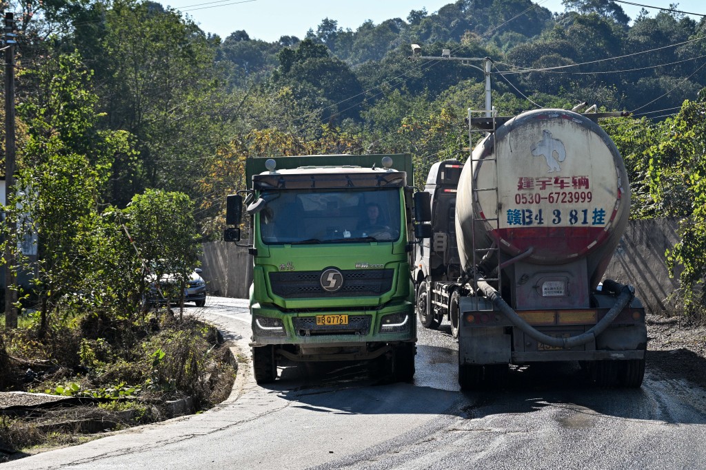 Photo by HECTOR RETAMAL / AFP  A truck (L) heading away from a rare earths mine drives past another heavy vehicle in Anyuan county, Ganzhou, in eastern China's Jiangxi province on November 21, 2025.