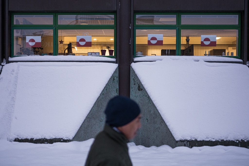 A man walks past a building with Greenland flags hanging in the windows in downtown Nuuk, Greenland, on January 19, 2026. (Photo by Jonathan NACKSTRAND / AFP)