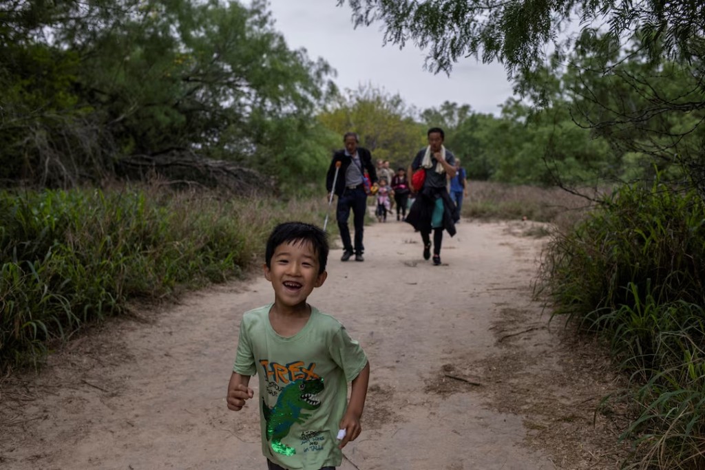 A five-year-old migrant boy from China chases his brother down a trail after he and his family crossed the Rio Grande river into the United States from Mexico in Fronton, Texas, U.S., April 5, 2023. REUTERS/Staff/File Photo