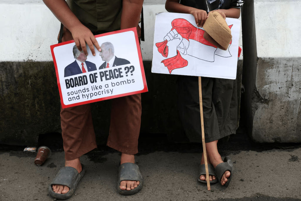 Boys in solidarity with Palestinians hold signs as they take part in a protest, outside the U.S. embassy, against Israel and demanding that the Indonesian government cancel the proposed multinational peacekeeping force for Gaza, following Indonesia's President Prabowo Subianto invitation to Washington later this month for the first meeting of U.S. President Donald Trump's Board of Peace, in Jakarta, Indonesia, February 13, 2026. REUTERS/Ajeng Dinar Ulfiana