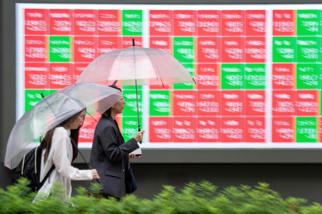 Pedestrians walk past an electronic quotation board displaying the Nikkei 225 stock prices on the Tokyo Stock Exchange along a street in Tokyo on June 25, 2026. AFP