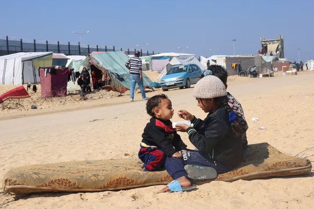 Displaced Palestinian girl, who fled her house due to Israeli strikes, feeds her brother at a tent camp, near the border with Egypt, in Rafah in the southern Gaza Strip, February 25, 2024. (REUTERS/Saleh Salem) Displaced Palestinian girl, who fled her house due to Israeli strikes, feeds her brother at a tent camp, near the border with Egypt, in Rafah in the southern Gaza Strip, February 25, 2024. (REUTERS/Saleh Salem)