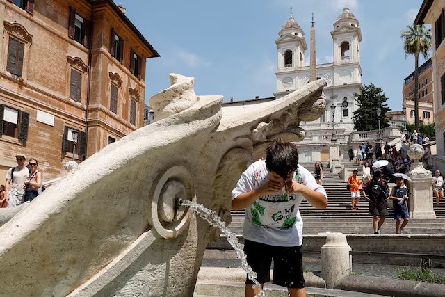 A boy cools off at the Barcaccia fountain near the Spanish steps during a heatwave, as temperatures are expected to rise further in the coming days, in Rome, Italy August 3, 2026. REUTERS/Remo Casilli/File Photo