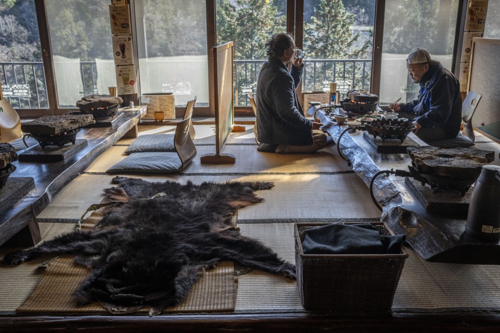 People eating next to a bear skin rug at a restaurant which offers bear meat in Chichibu, Saitama prefecture. (AFP)