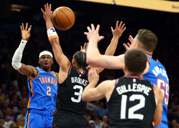 Shai Gilgeous-Alexander passes the ball under pressure from Phoenix Suns forward Dillon Brooks. REUTERS