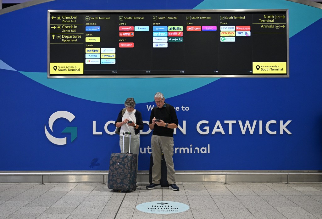 Photo by JUSTIN TALLIS / AFP  Passengers stand with their luggage underneath an information display board in the South Terminal of London Gatwick airport near Crawley, southern England on September 9, 2026, following second day of major disruption due an issue affecting the NATS air traffic control systems.