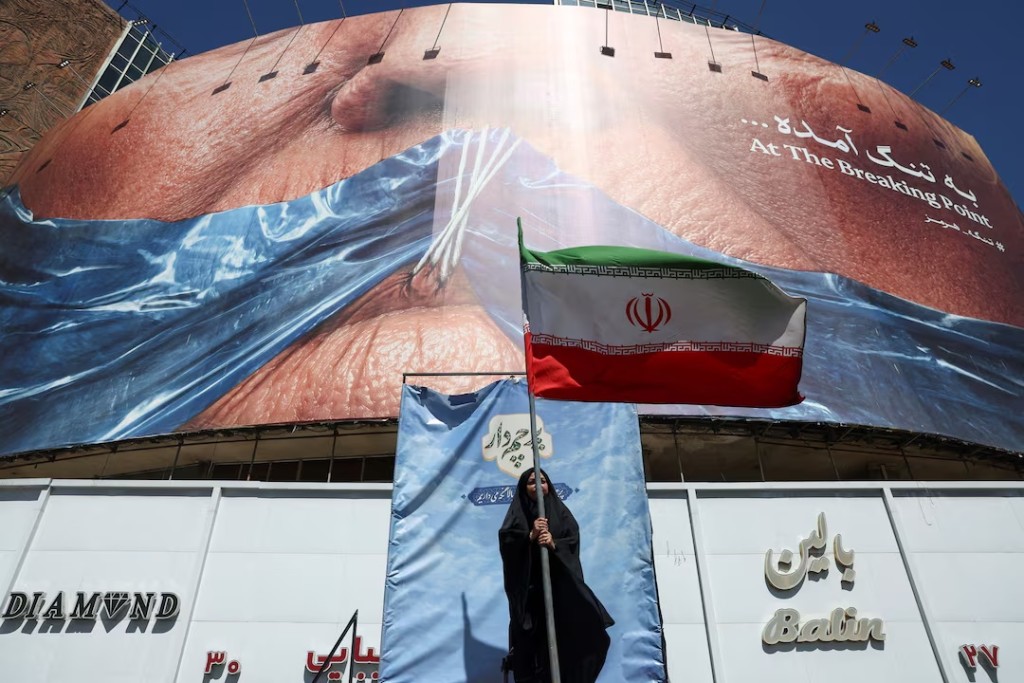 A woman holds an Iranian flag near an anti-U.S. billboard depicting U.S. President Donald Trump and the Strait of Hormuz, in Tehran, Iran, May 25, 2026. Majid Asgaripour/WANA (West Asia News Agency) via REUTERS