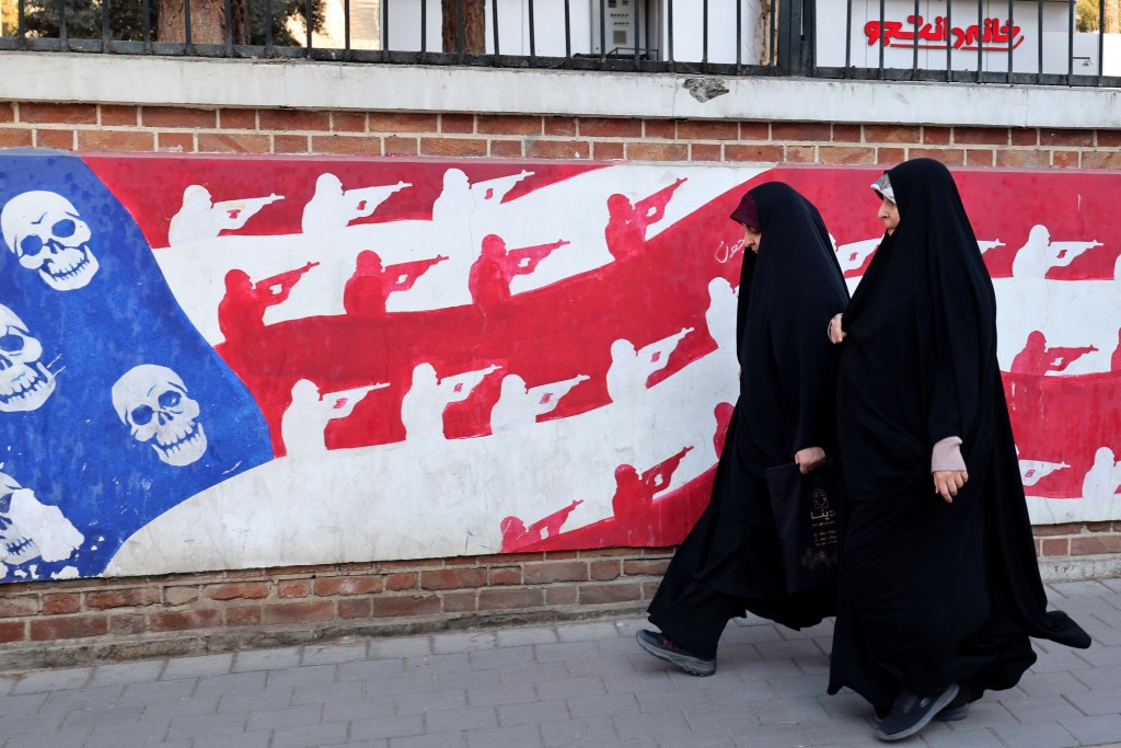 Photo by ATTA KENARE / AFP  Women walk past a mural painted on the outer walls of the former US embassy in Tehran, colloquially-referred to as the "Spy Den,"on February 1, 2026.