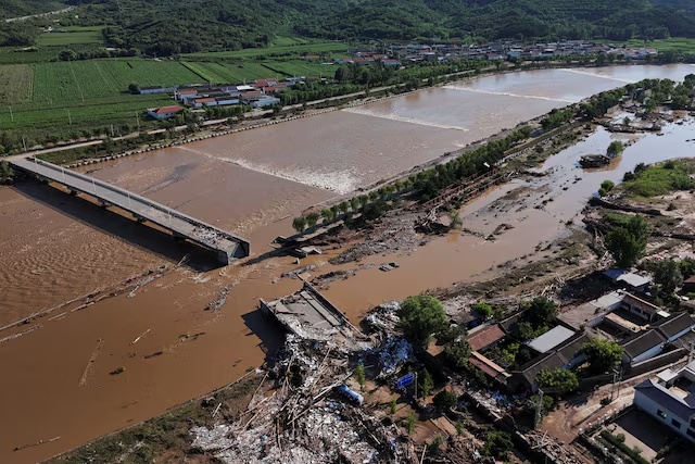 A drone view shows damaged roads and fallen trees next to the overflowing Qingshui river after heavy rainfall flooded the area, in Miyun district of Beijing, China July 29, 2025. REUTERS/Florence Lo/File Photo