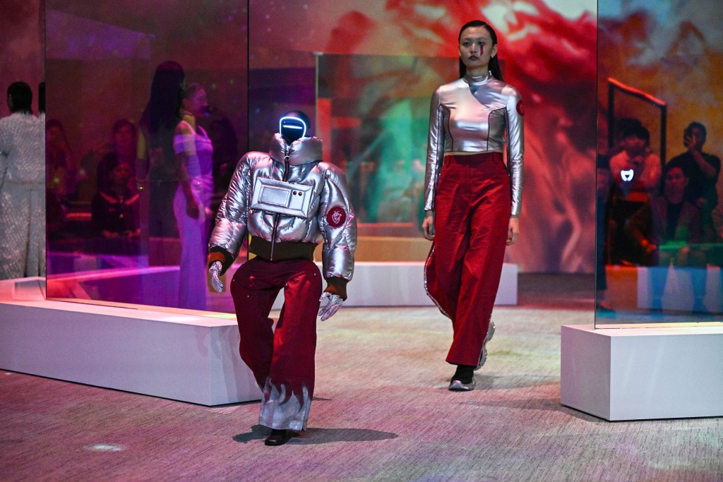 A humanoid robot and a model present creations at Galaxy Corporation's "Mach33: Physical AI Fashion Show" in seoul on May 28, 2026. (Photo by Pedro PARDO / AFP)
