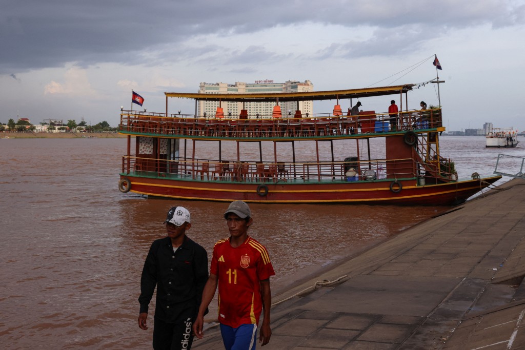People walk past a tourist boat in Cambodia. (File Photo)