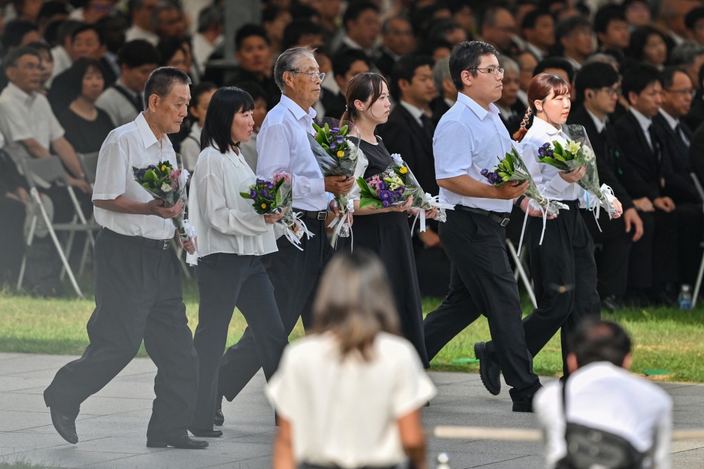 Invited guests carry bouquets of flowers to lay at the Memorial Cenotaph during the Peace Memorial Ceremony to mark the 80th anniversary of the world's first atomic bomb attack, in the city of Hiroshima on August 6, 2025. (Photo by Richard A. Brooks / AFP)