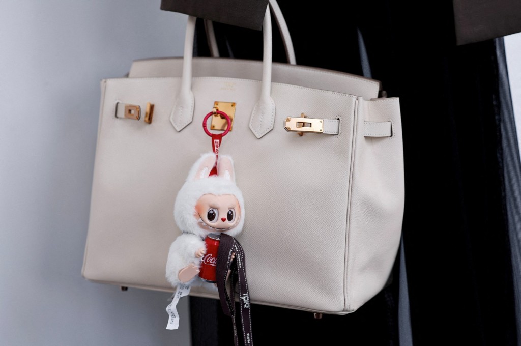 A Labubu toy hangs from a bidder's Hermes bag at an auction by Yongle International Auction in Beijing, China. REUTERS