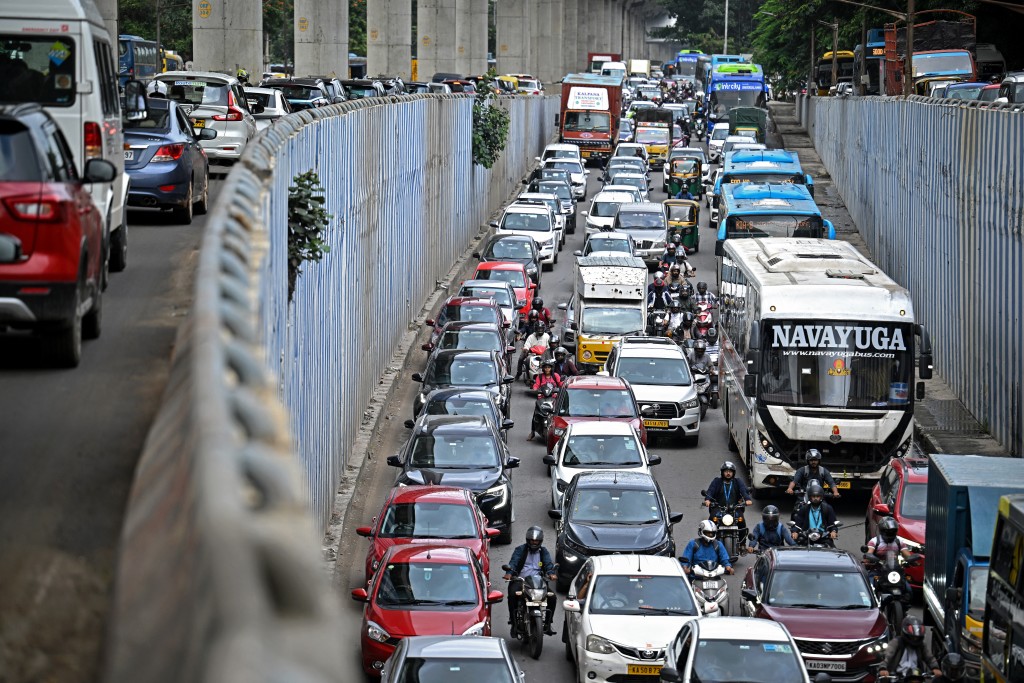 Photo by IDREES MOHAMMED / AFP  In this photograph taken on October 15, 2025, people commute through traffic in Bengaluru.